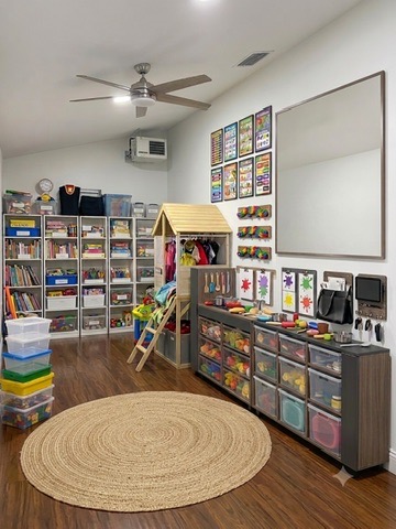Kids playroom after organizing — toys neatly sorted into labeled fabric bins on white shelves